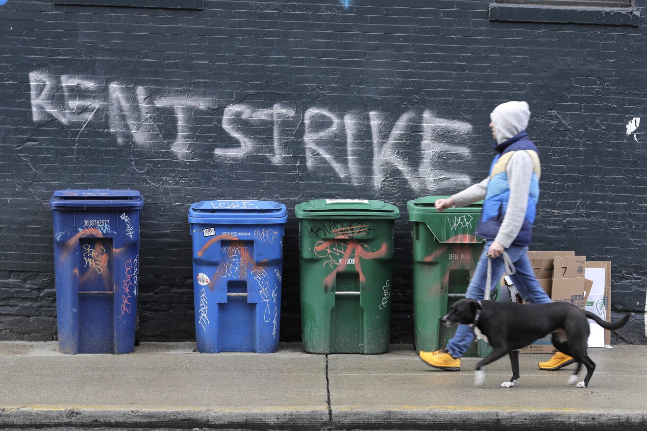 A pedestrian walks past graffiti that reads "Rent Strike" Wednesday, April 1, 2020, in Seattle's Capitol Hill neighborhood.